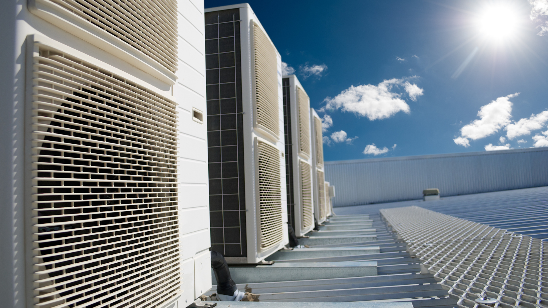 A row of air conditioners are lined up on the side of a building.