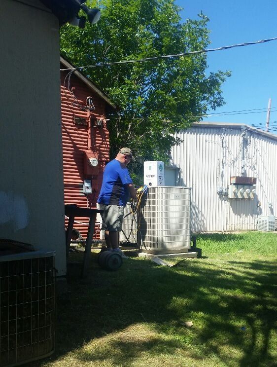 A man in a blue shirt is working on an air conditioner