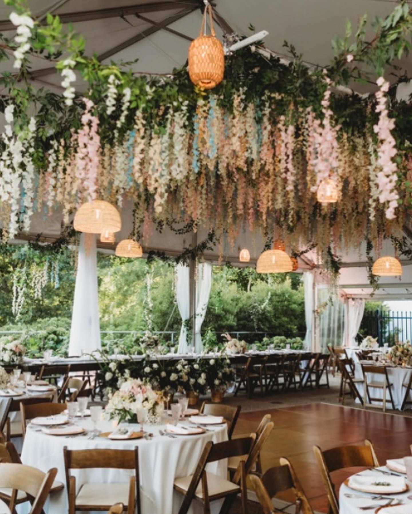 A large room with tables and chairs and flowers hanging from the ceiling