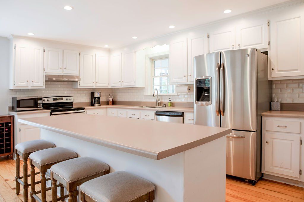 A kitchen with white cabinets , stainless steel appliances , and a large island.