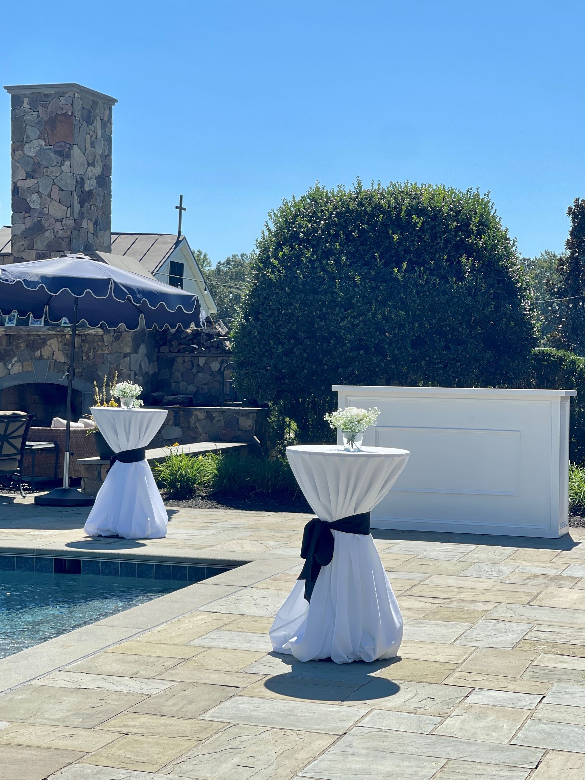 A patio with tables and umbrellas next to a pool
