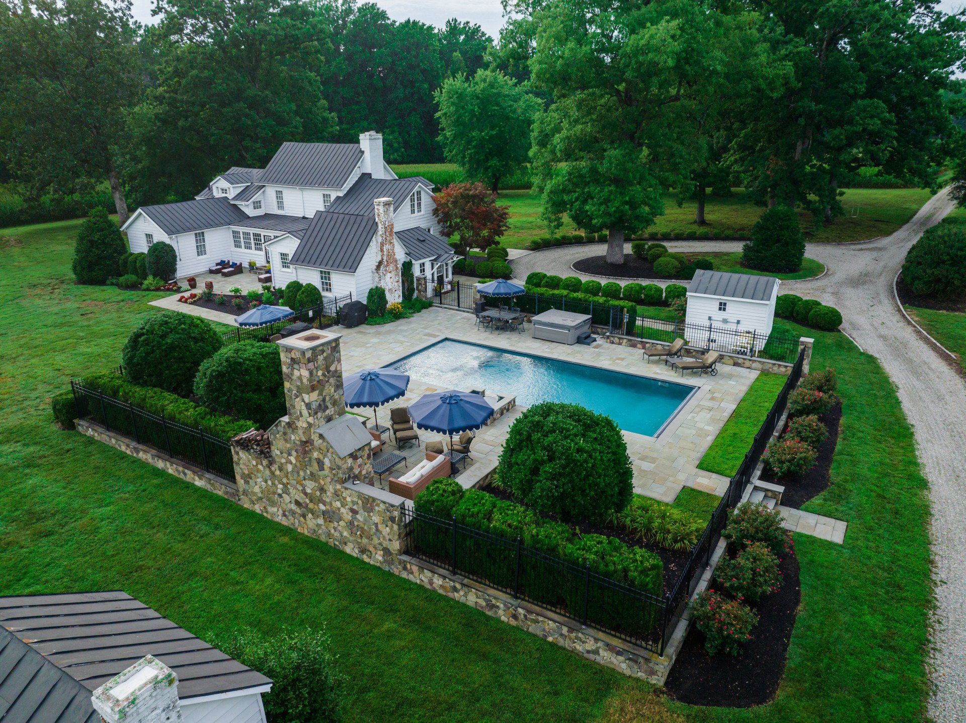 An aerial view of a large house with a large swimming pool in the backyard.