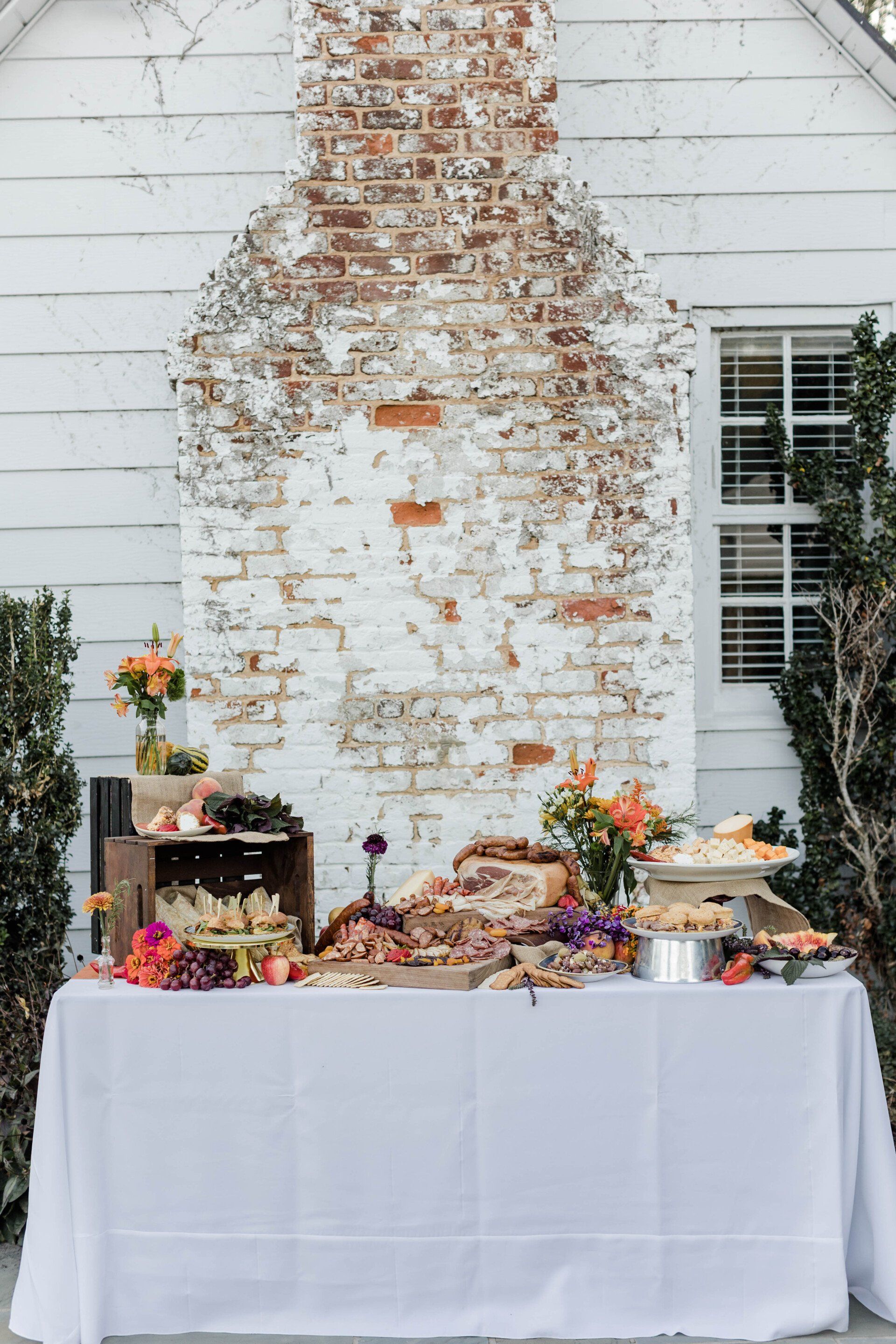 A table with a white tablecloth is sitting in front of a brick wall.