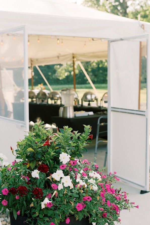 A white tent with flowers in front of it.