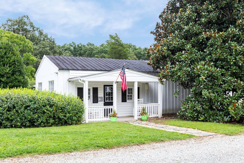A white house with a porch and an american flag on it.
