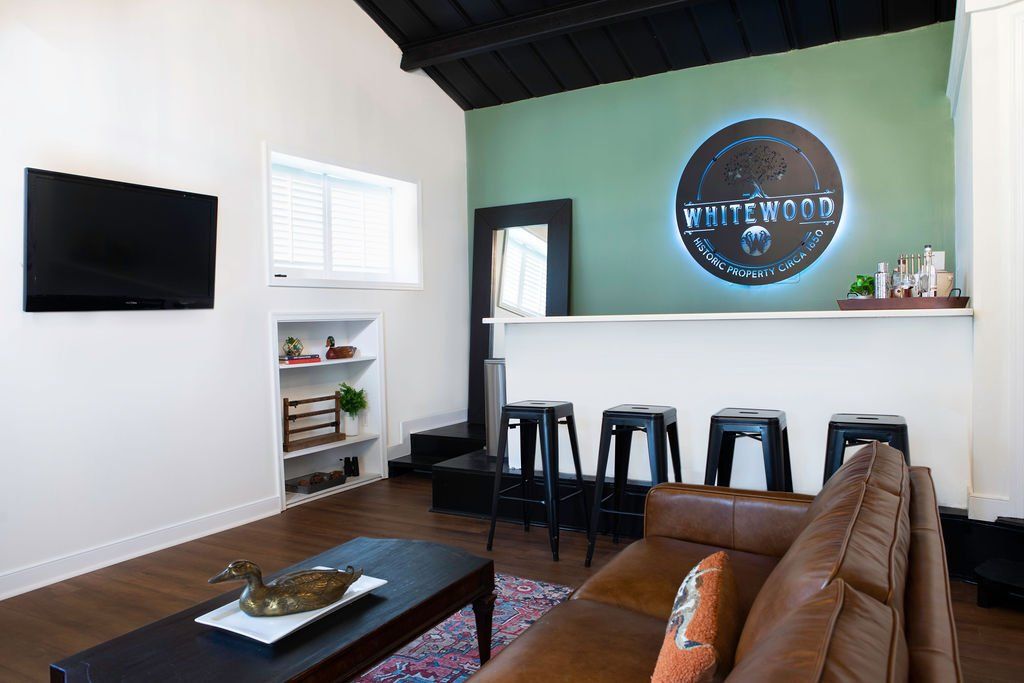 A living room with a couch , table , television and bar.