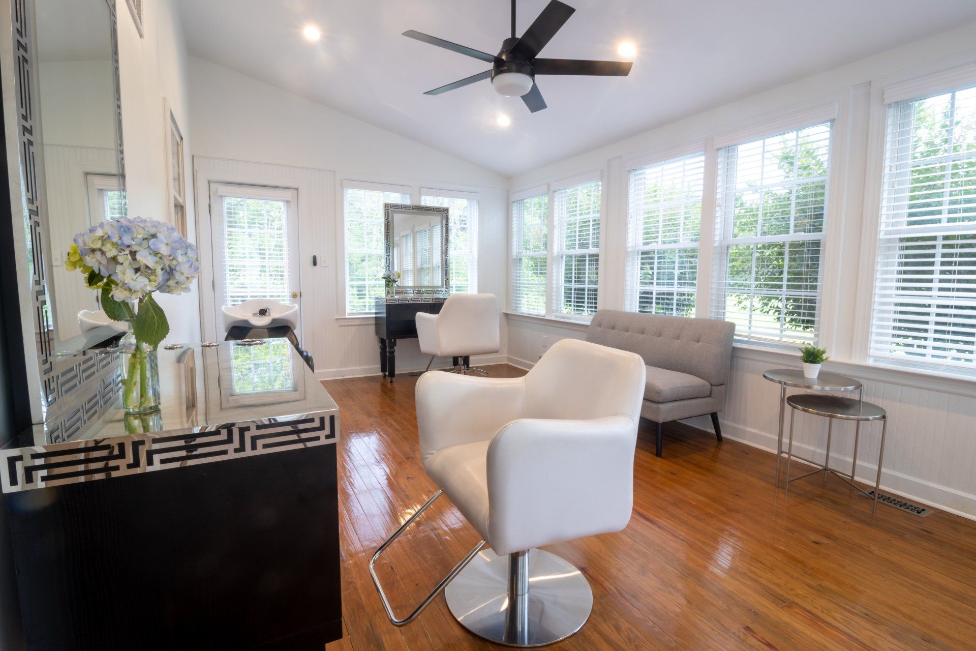 There is a chair in the middle of the room with a ceiling fan.