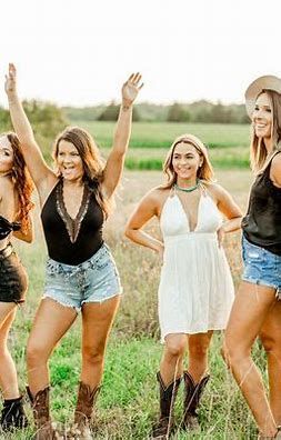 A group of women are standing in a field with their arms in the air.