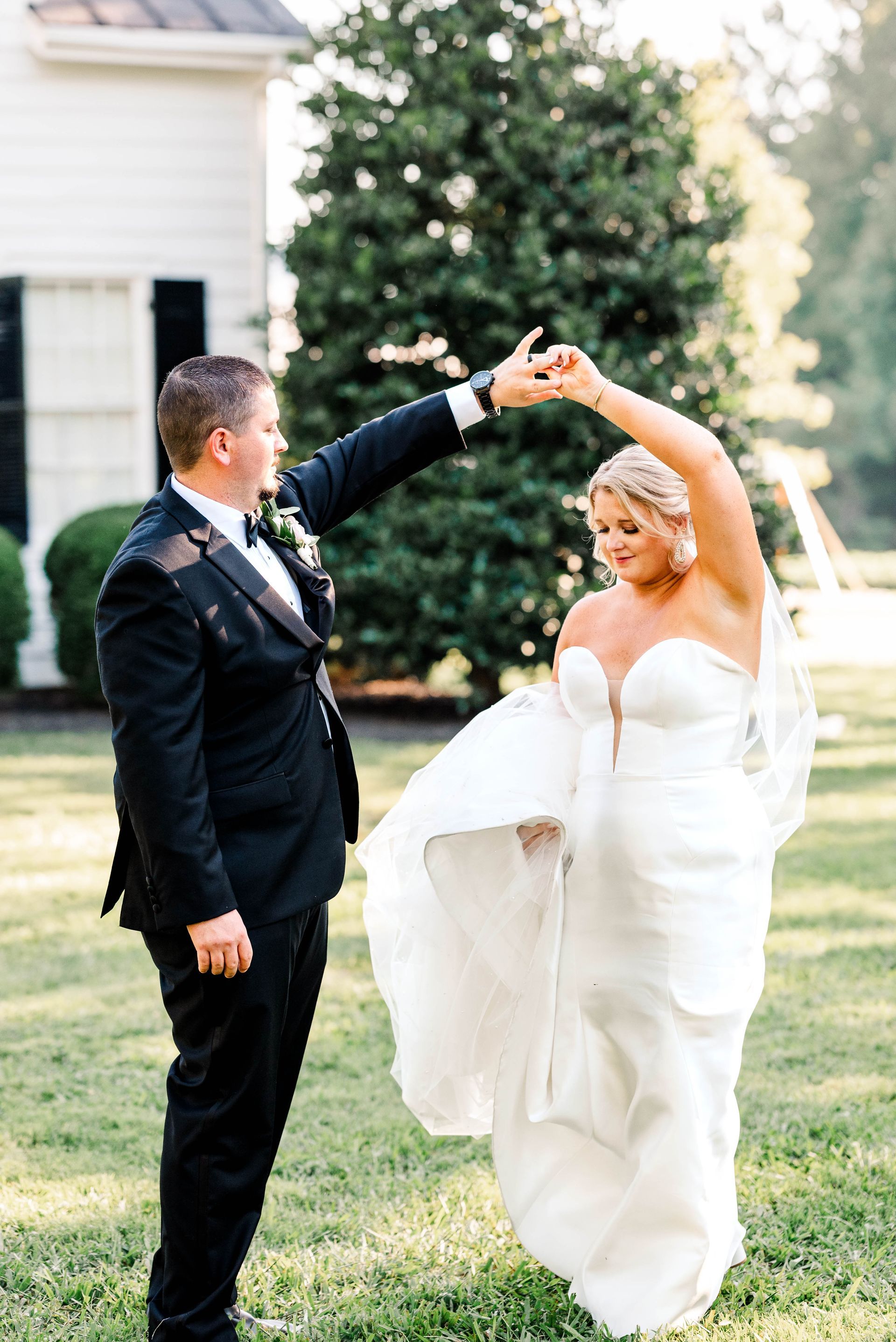 A bride and groom are dancing in a field.