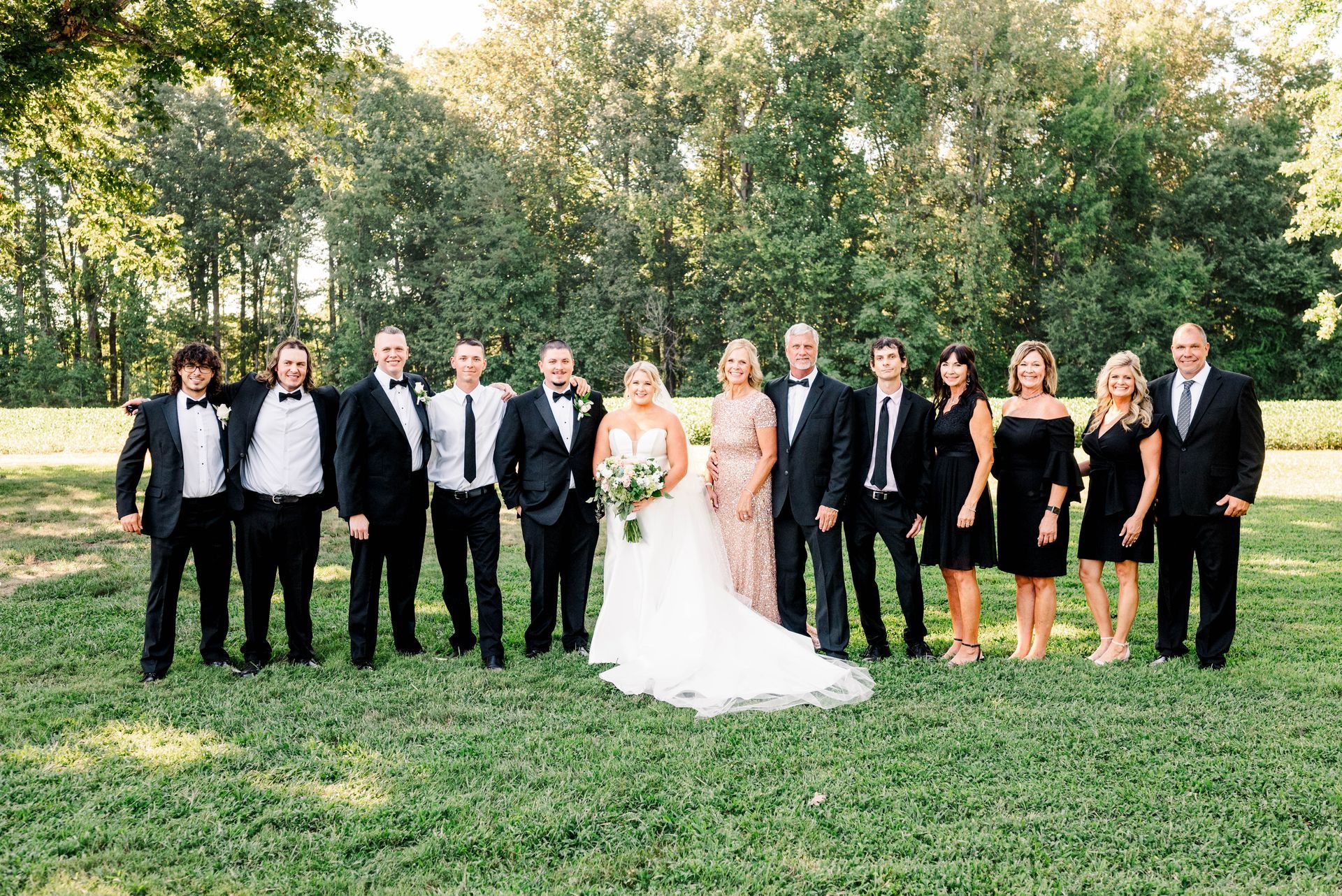A bride and groom are posing for a picture with their wedding party.