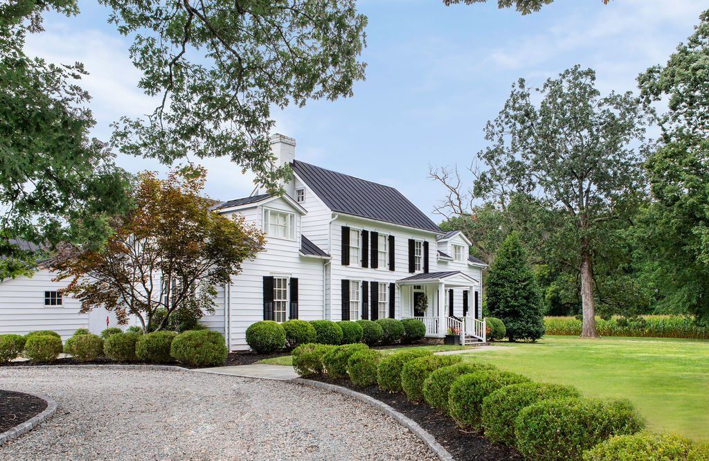 A large white house with a gravel driveway leading to it