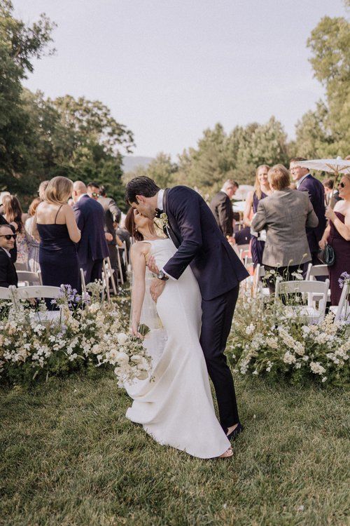 A bride and groom are kissing in front of their wedding guests.