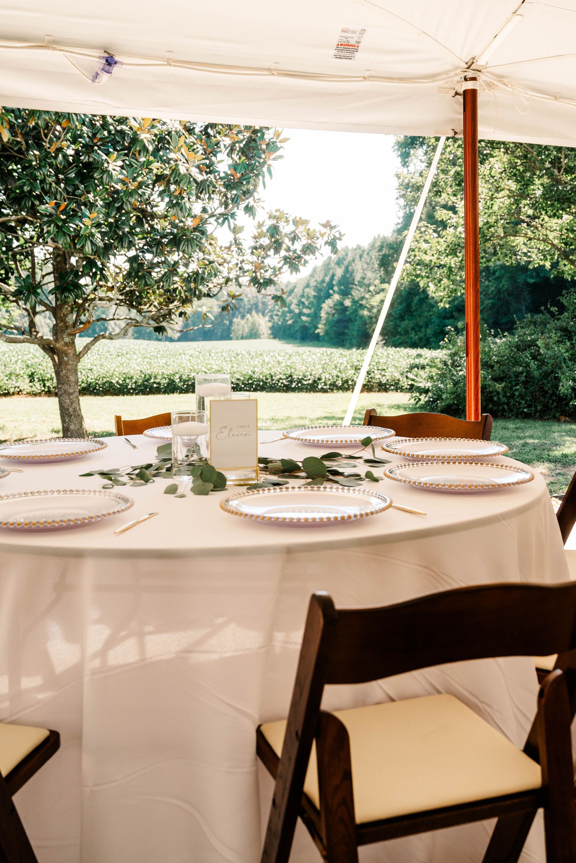 A table set for a wedding reception under a tent.