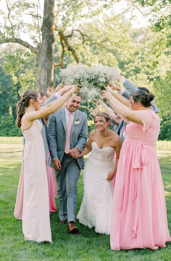 A bride and groom are walking through a circle of their wedding party.