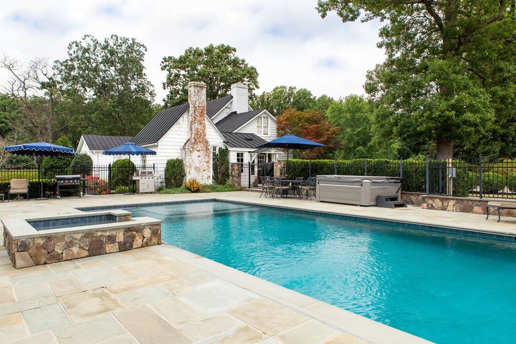 There is a large swimming pool in the backyard of a house.