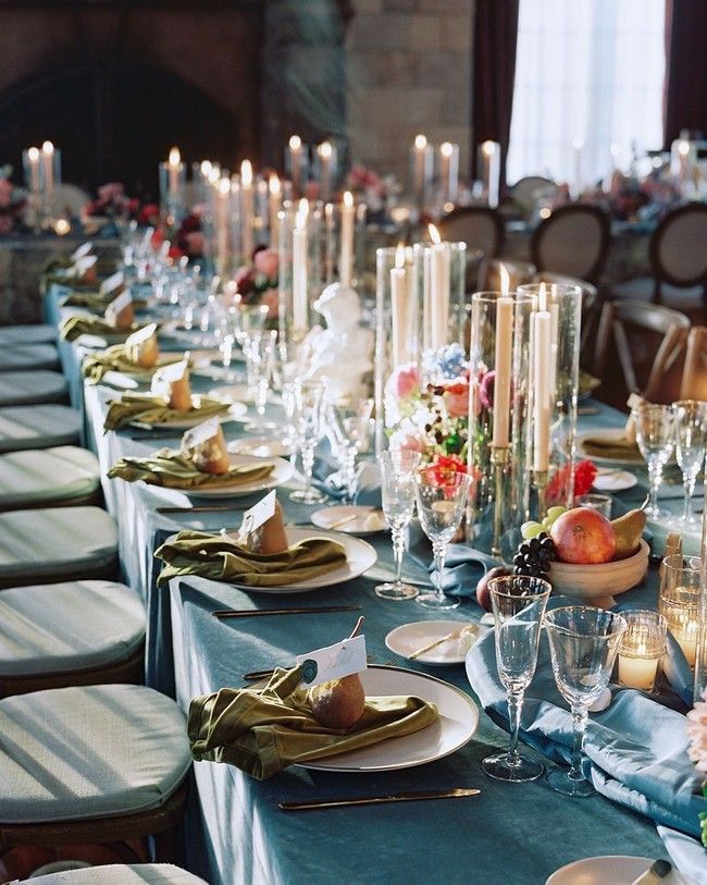 A long table with plates candles and fruit on it