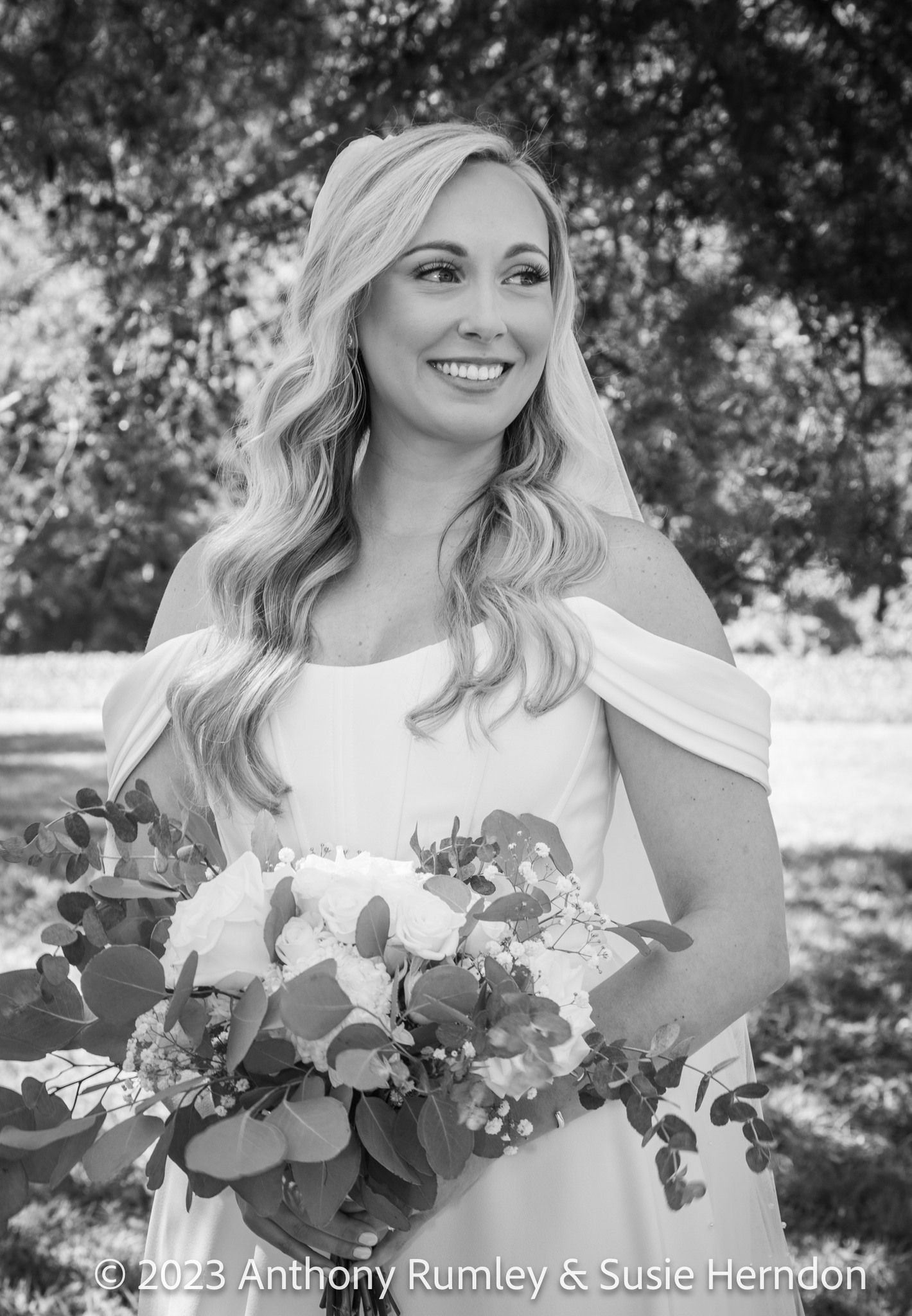 A black and white photo of a bride in a wedding dress holding a bouquet of flowers.