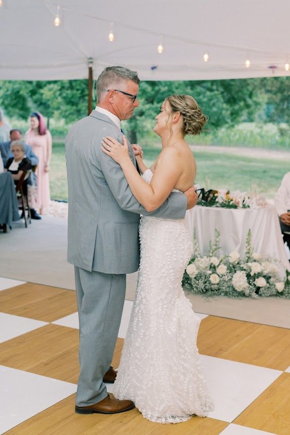 A bride and groom are dancing on a wooden dance floor.