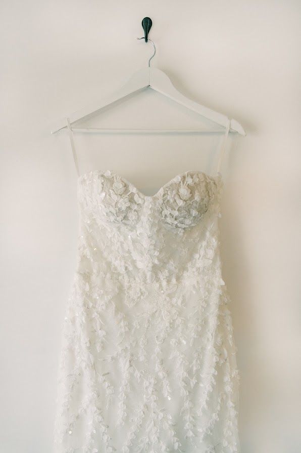 A white wedding dress is hanging on a white hanger.