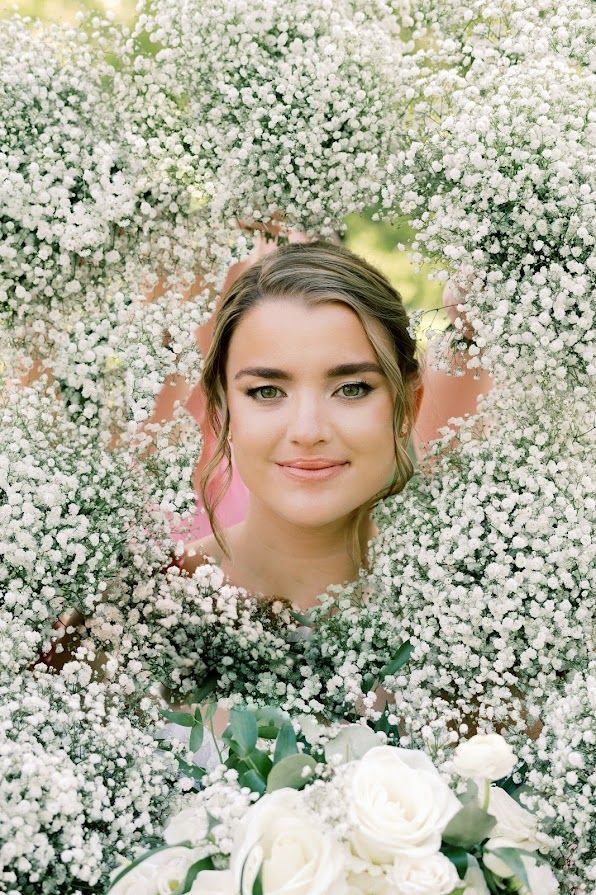 A woman is standing in a field of baby 's breath flowers.