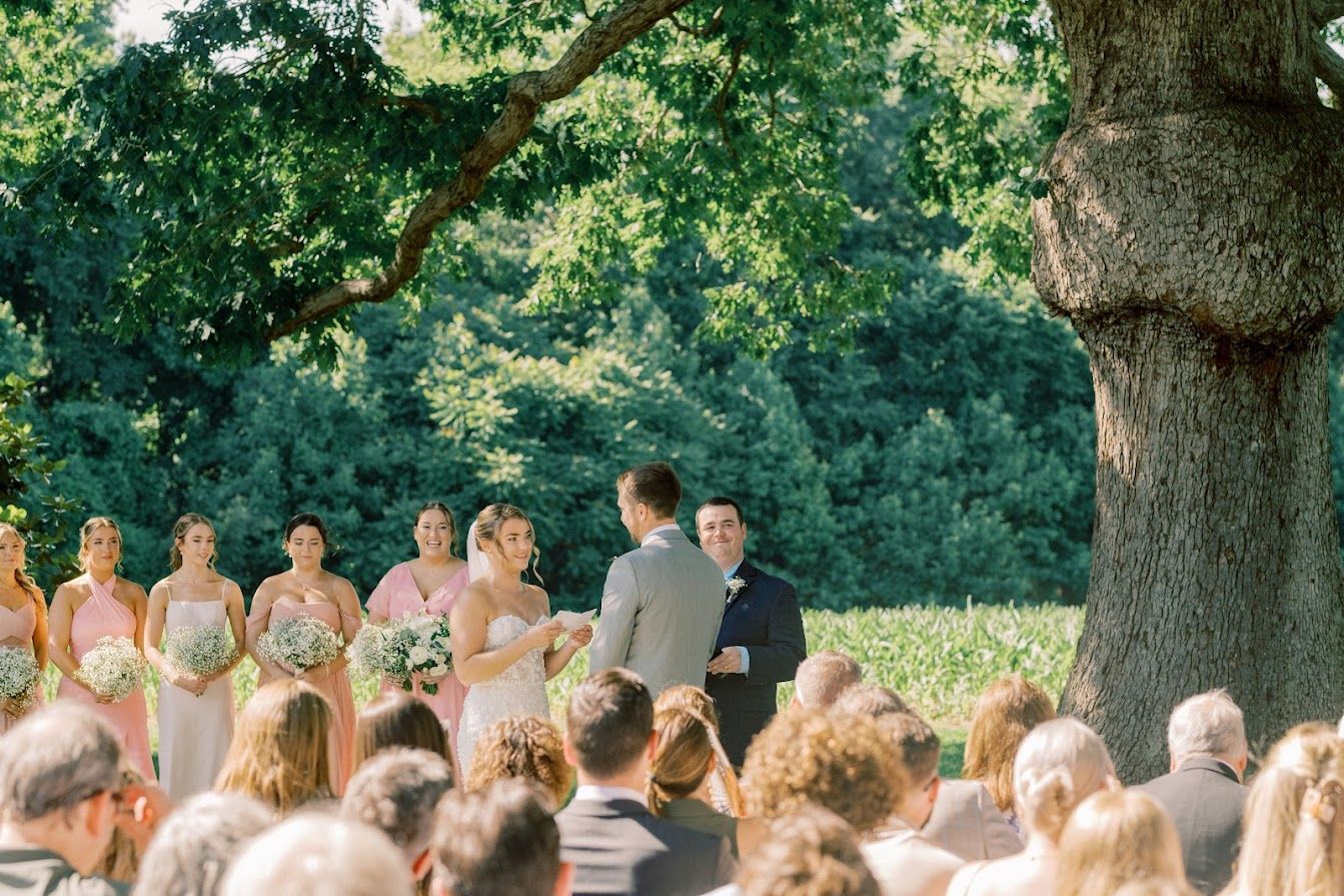 A bride and groom are getting married in front of a large tree.