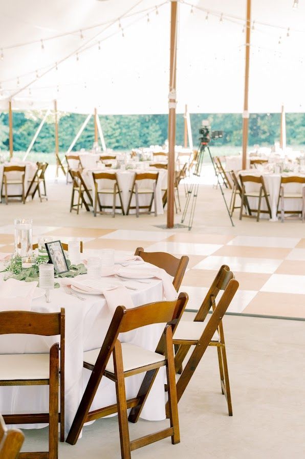 A large tent with tables and chairs set up for a wedding reception.