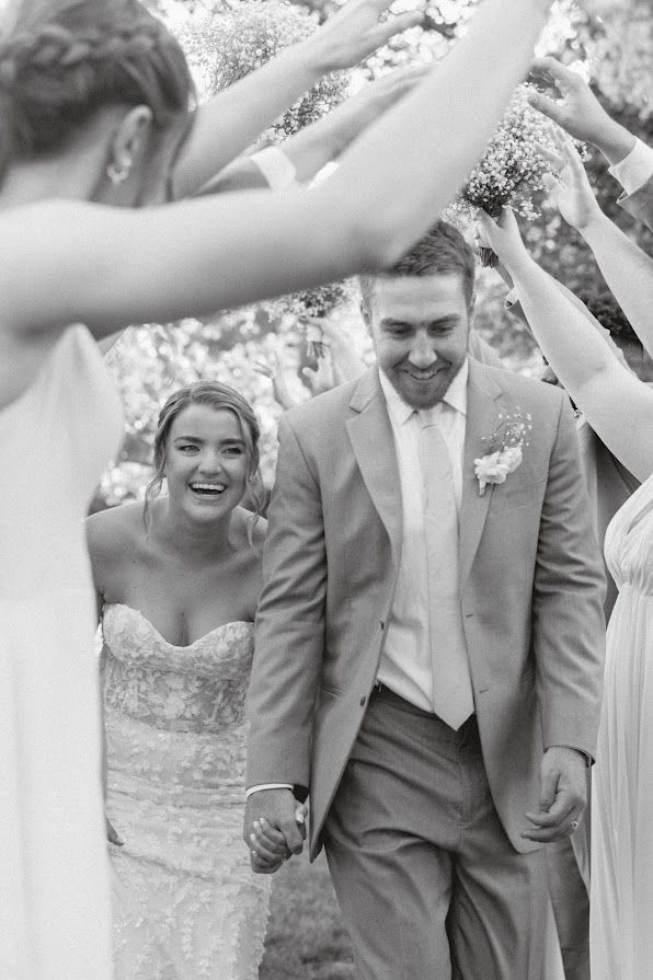 A black and white photo of a bride and groom holding hands.
