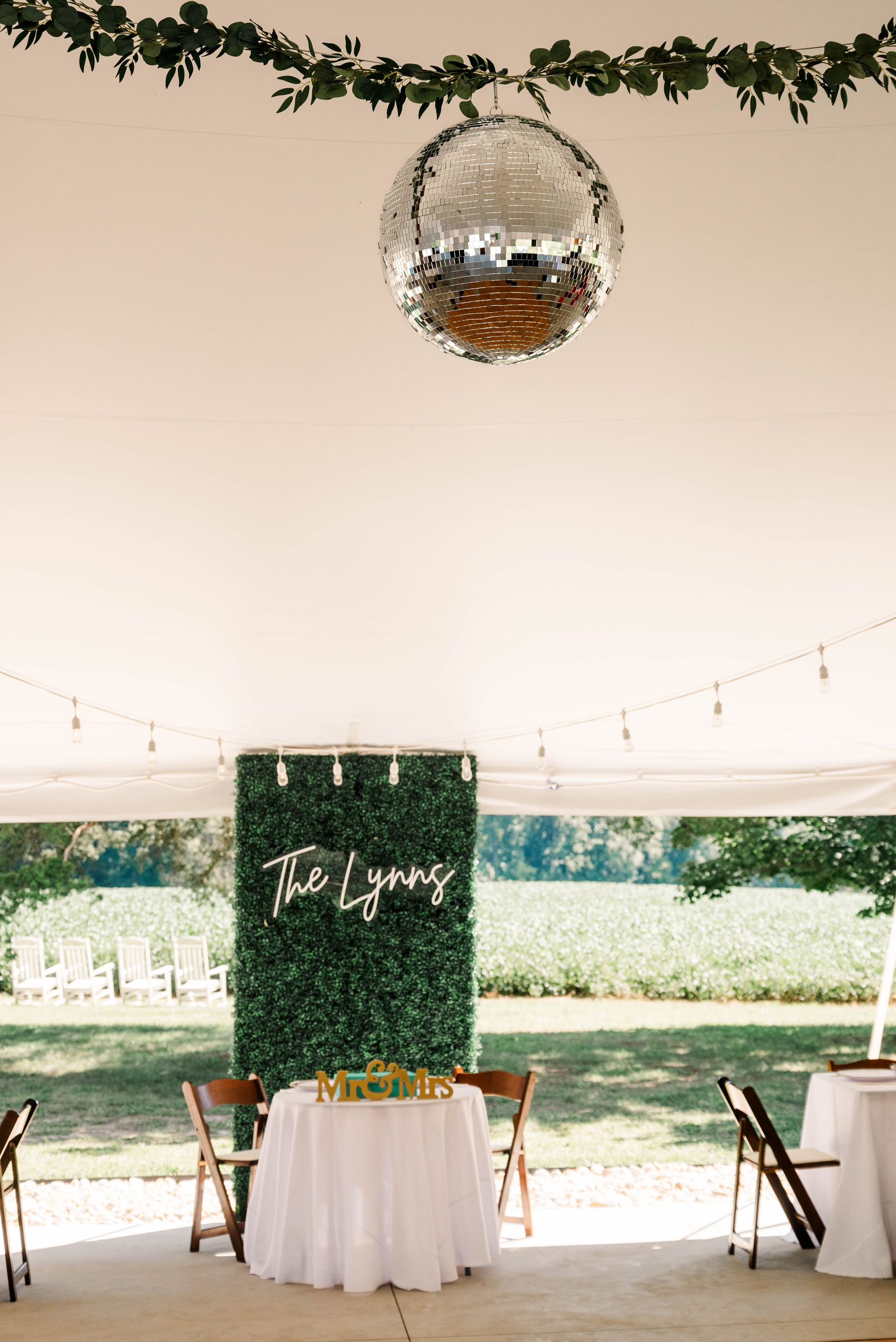 A table and chairs under a tent with a disco ball hanging from the ceiling.