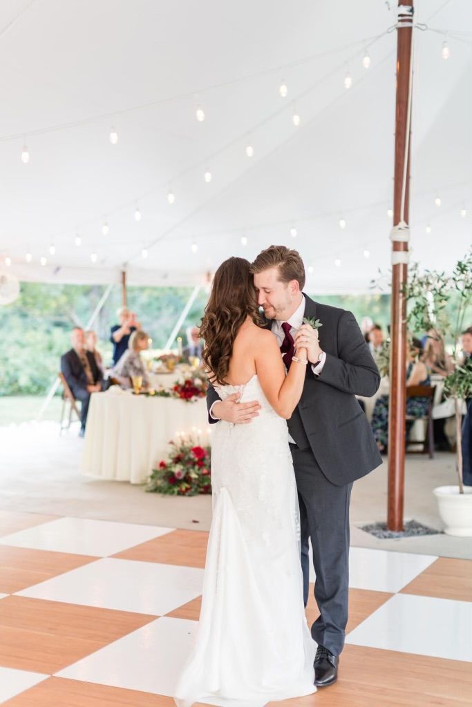A bride and groom are dancing under a tent at their wedding reception.