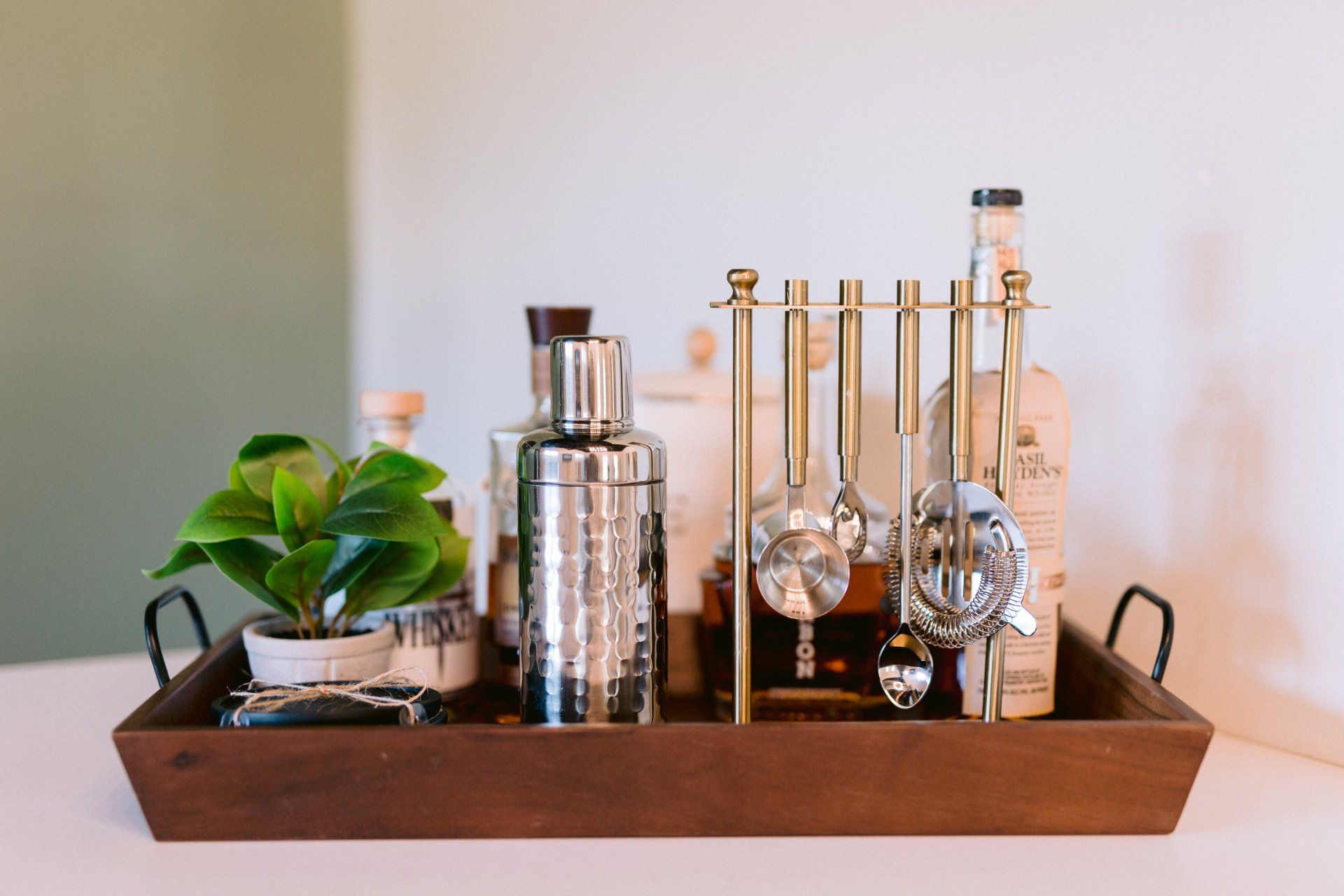 A wooden tray filled with bottles and utensils on a table.