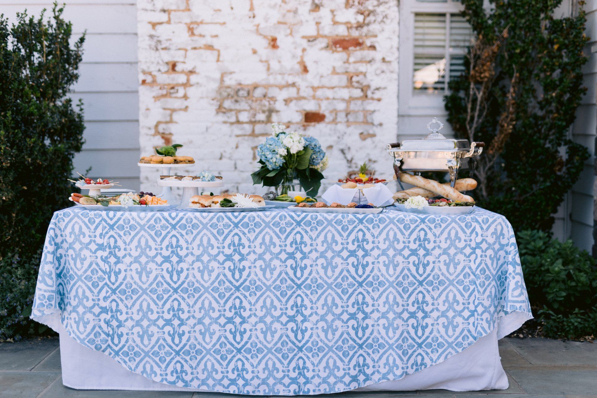 A table with a blue and white tablecloth and plates of food on it.