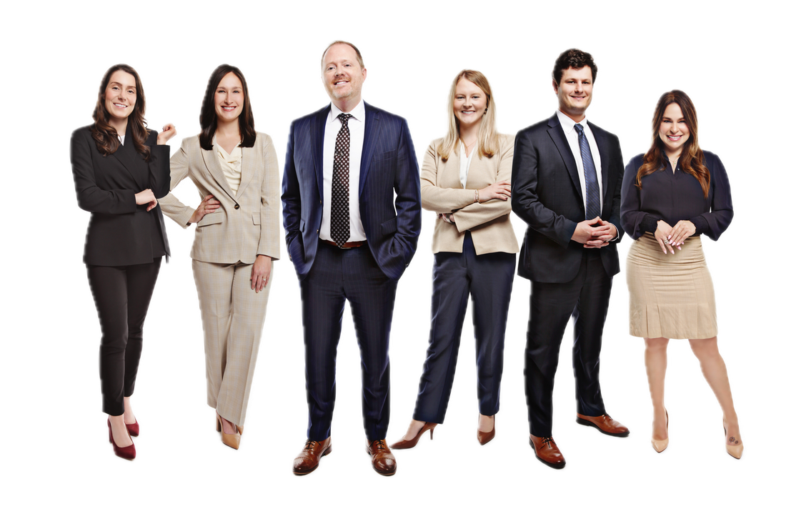 Five professionals in business attire stand together, smiling, against a white background.