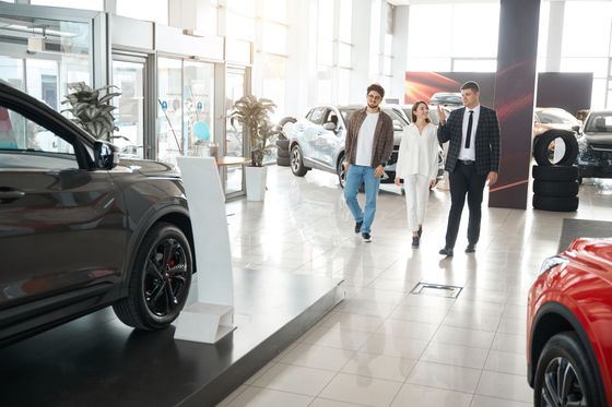 A man and a woman are looking at cars in a car showroom.