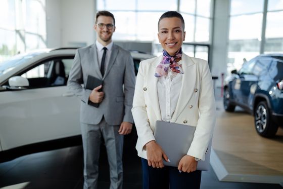 A man and a woman are standing next to each other in a car showroom.