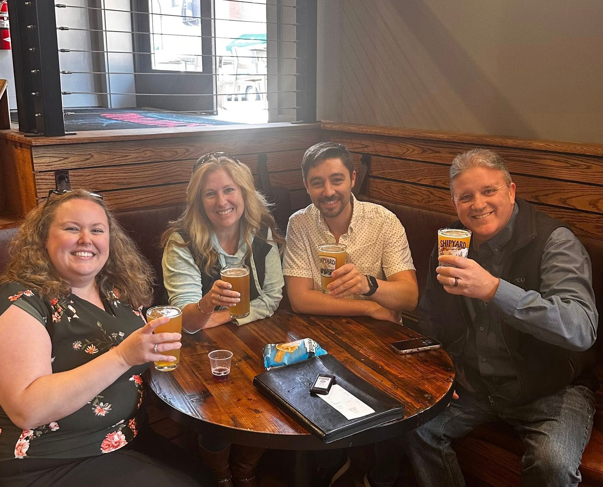 A group of people are sitting at a table drinking beer.