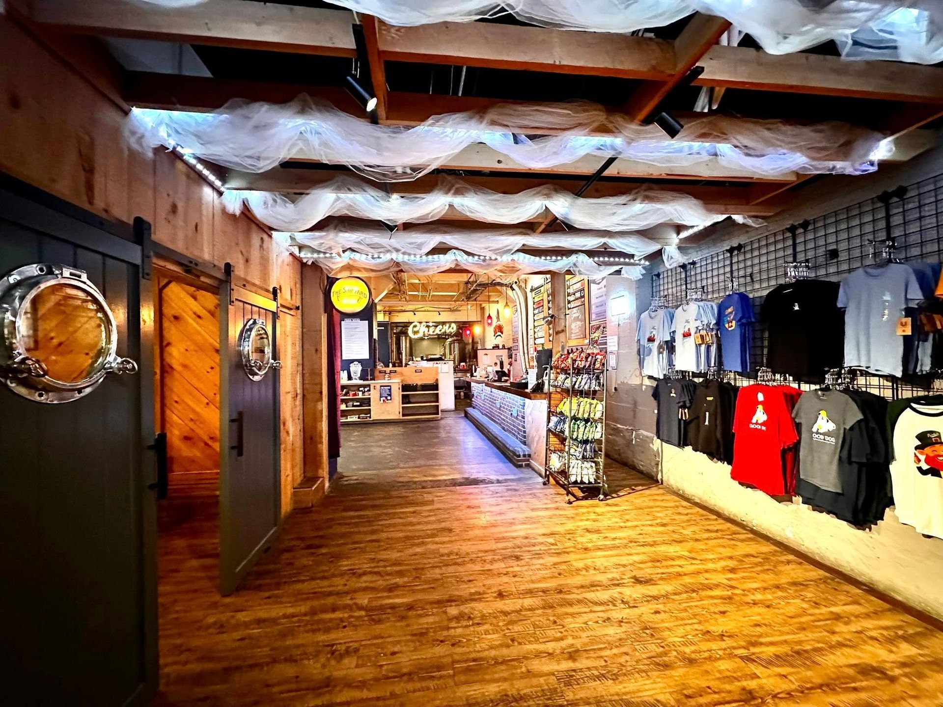 A long hallway with a lot of shirts hanging on the wall in a store.
