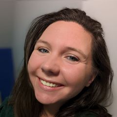A woman is smiling for the camera in front of a black background.