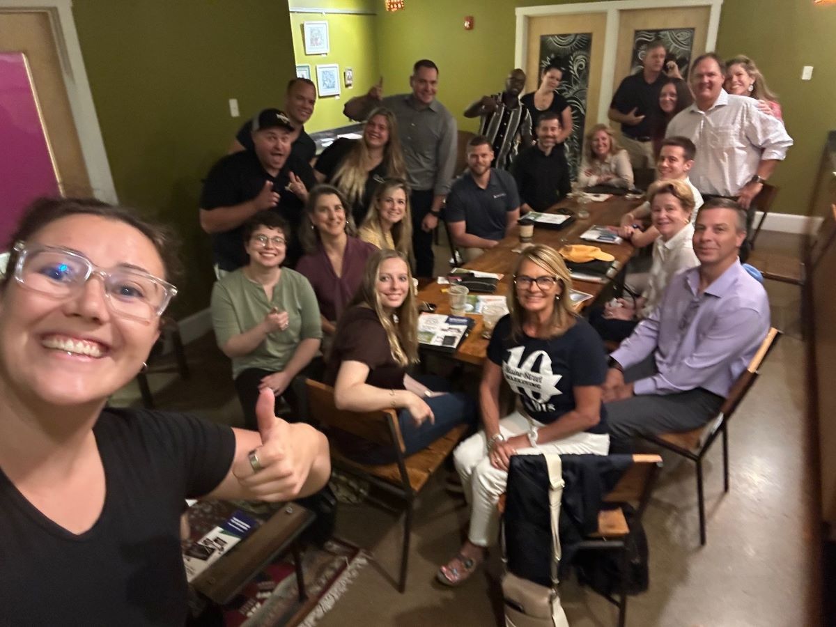 A group of people are sitting around a table for the Portland TBD networking meeting.