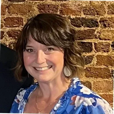 A young man with a beard is wearing a black shirt and smiling at the camera.