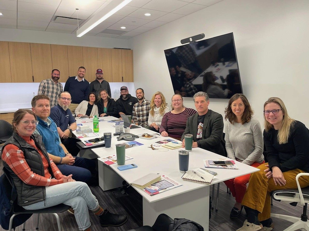 A group of people are sitting around a long table in a conference room.