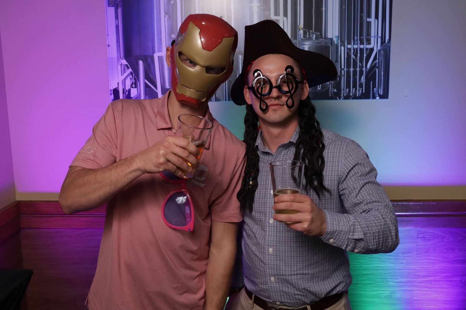 Two men wearing masks and glasses are posing for a picture in a photo booth.