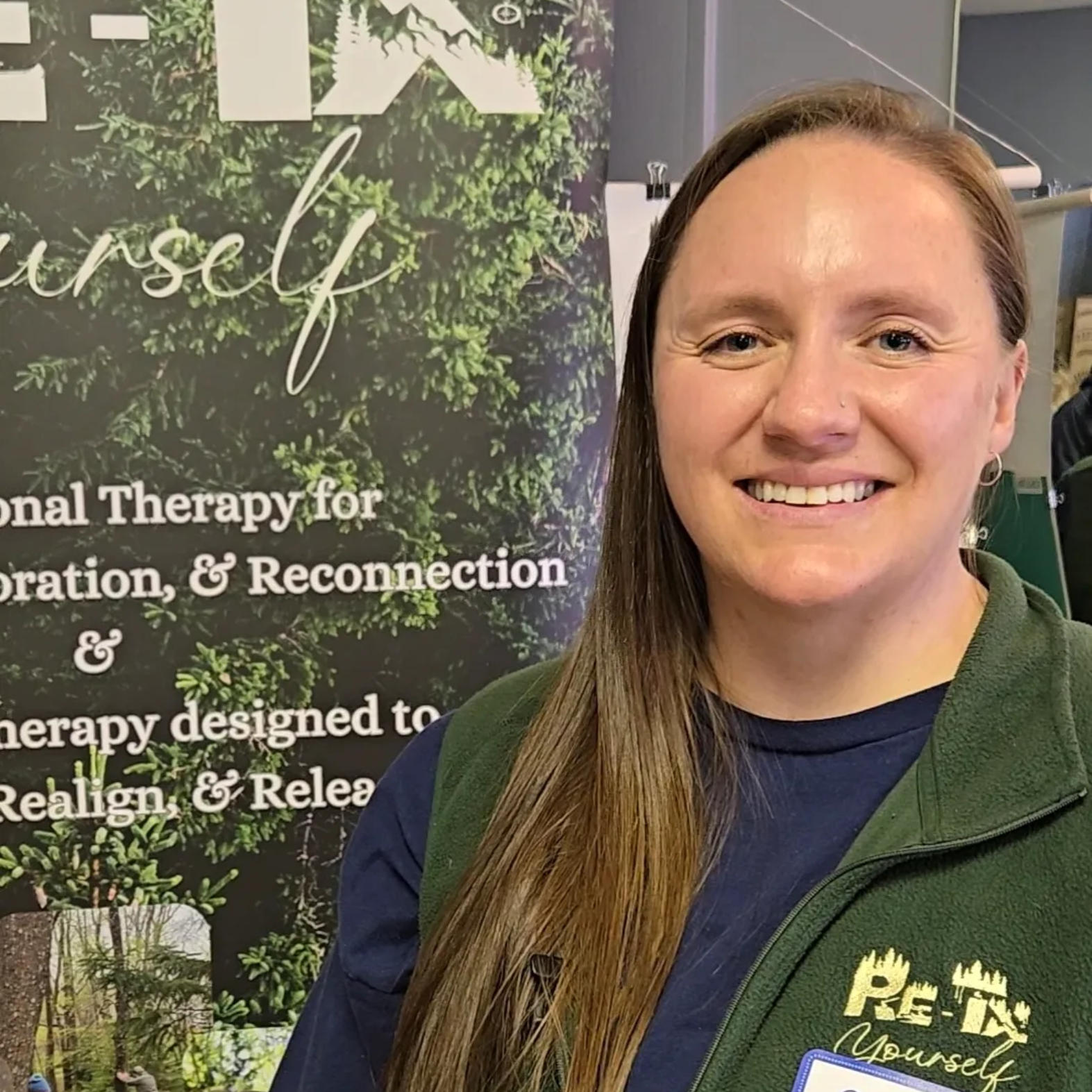 Man with short curly gray hair, wearing earbuds, looking directly at the camera. He wears a dark blue jacket.