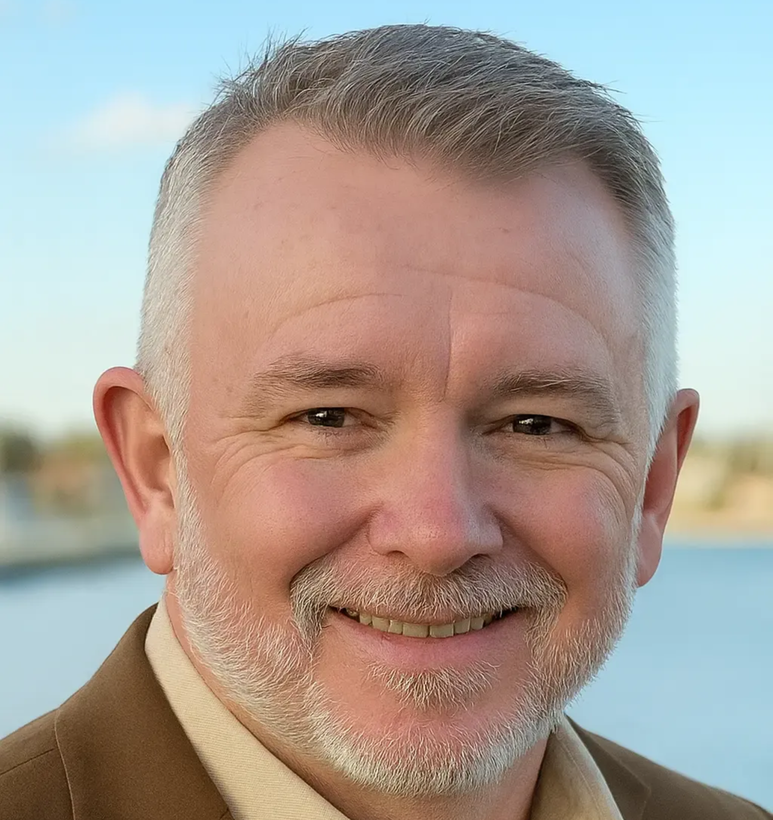 A young man with a beard is wearing a black shirt and smiling at the camera.