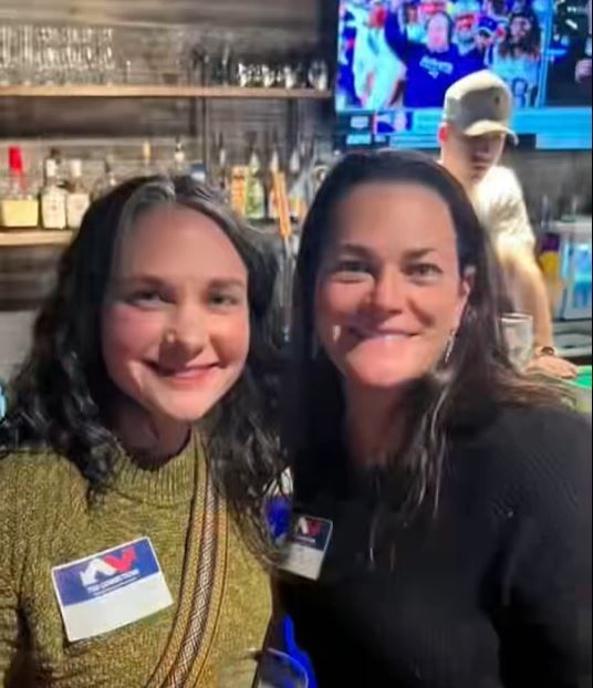 Two women are posing for a picture together in a bar.
