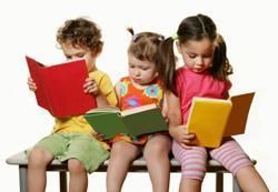 Three children reading books of different colors while sitting together.
