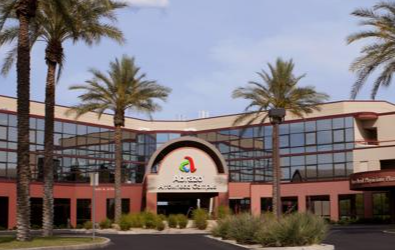 Red brick building with glass windows, palm trees, and a sign for a center.