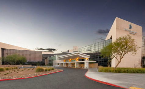 Hospital exterior, desert landscape, clear sky, modern architecture, curved driveway.