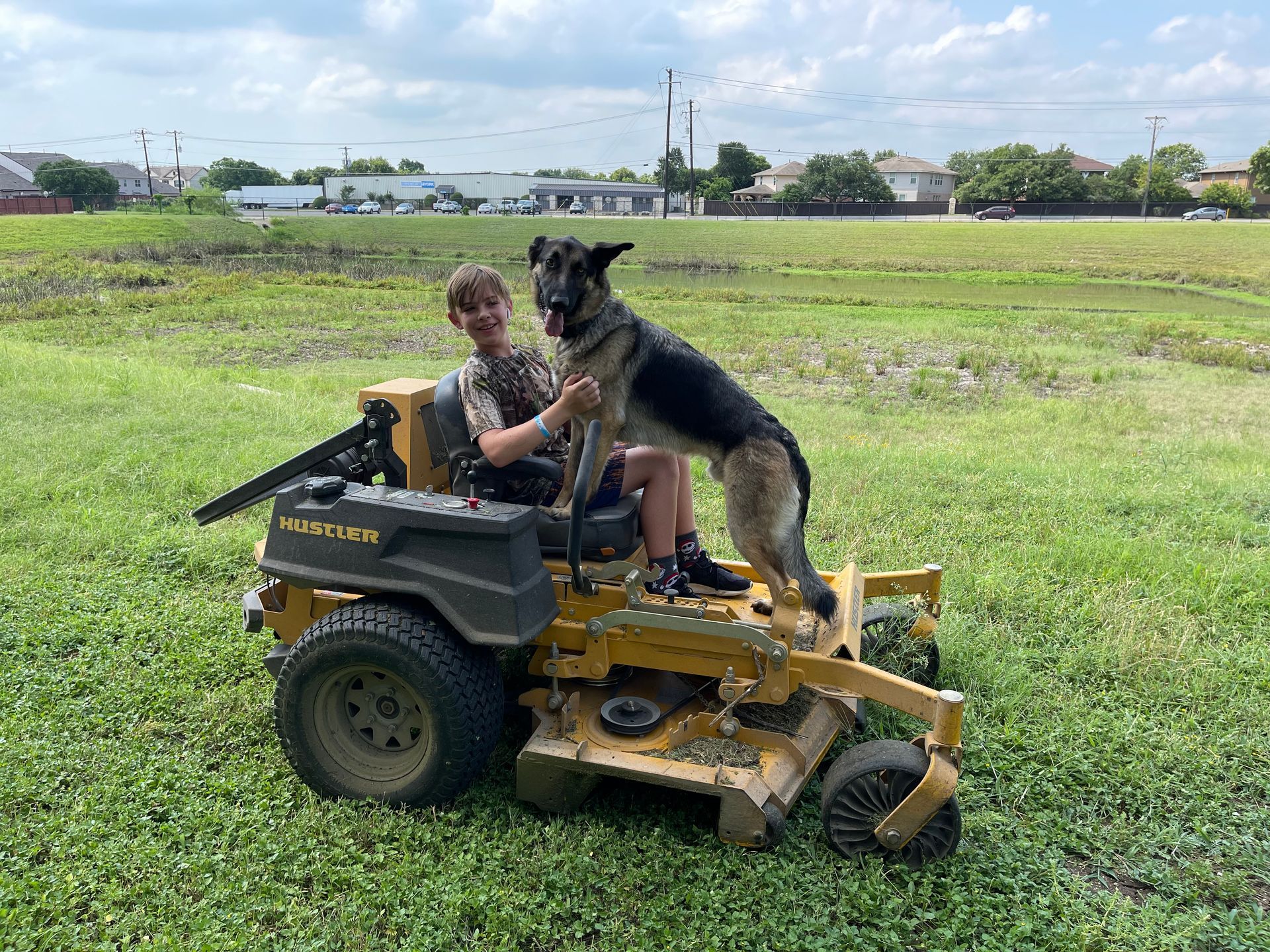 A man is mowing a lush green lawn with a red lawn mower.