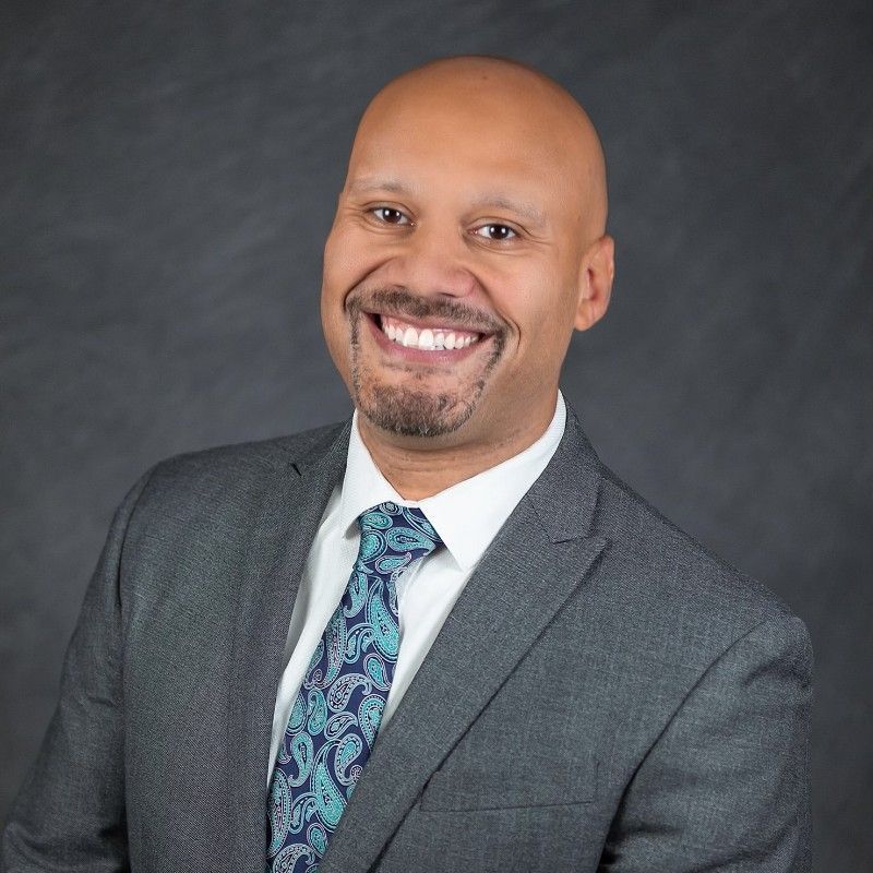 A man in a suit and tie is smiling for the camera.