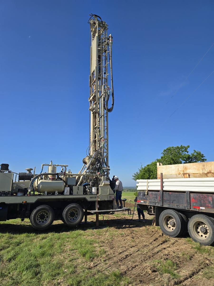 A drilling rig mounted on a service truck is used for residential well pump repair and installations in a field.